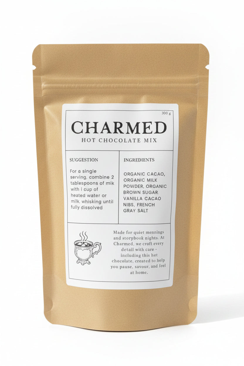 A stand-up pouch of Charmed Hot Chocolate Mix in a matte gold finish with a large white label