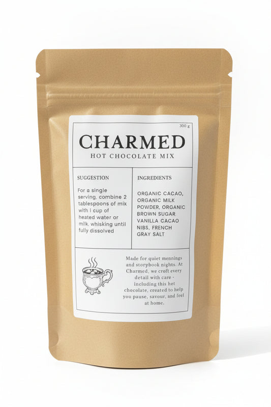 A stand-up pouch of Charmed Hot Chocolate Mix in a matte gold finish with a large white label