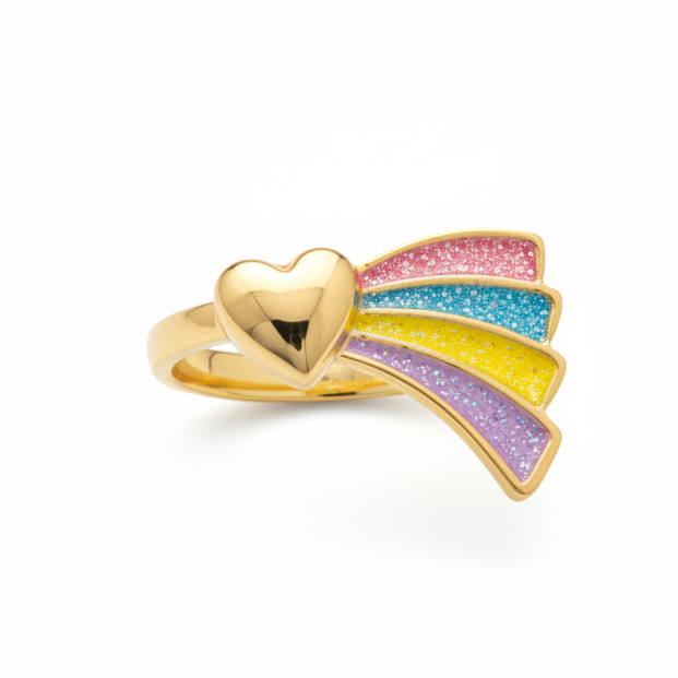 A small ring with a gold heart and rainbow charm inside a pink Great Pretenders box, photographed from above on a wooden surface.