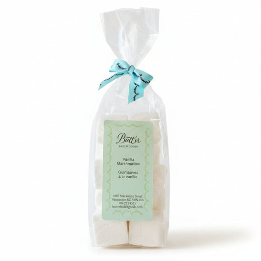 A clear plastic bag containing several white rectangular bars of butter, tied with a light blue ribbon, and labeled 'Butter' 